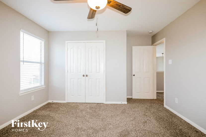 A bedroom with a carpeted floor and a ceiling fan.