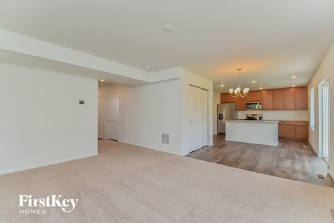 A spacious living room with a kitchen in the background.