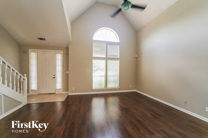 an empty living room with a ceiling fan and a large window