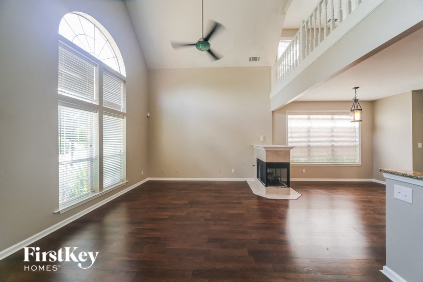 an empty living room with a large window and a ceiling fan