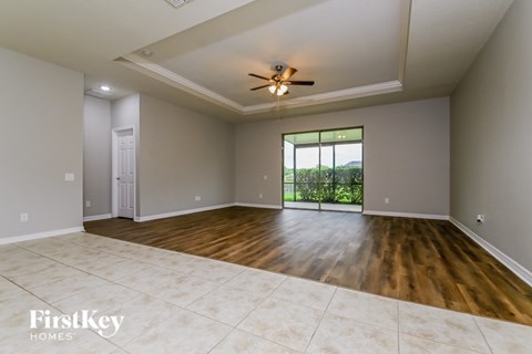 A spacious room with a ceiling fan and a view of greenery outside the window.
