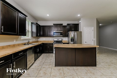 A kitchen with black cabinets and a wooden island.