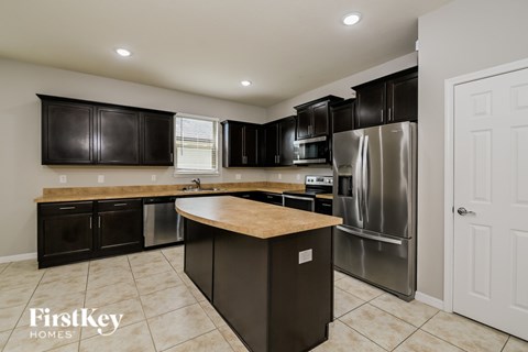A kitchen with a refrigerator, oven, and sink.