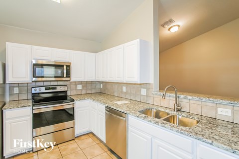 A kitchen with white cabinets and granite countertops.
