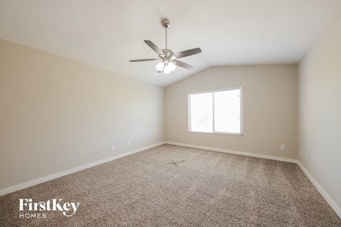 a spacious living room with carpet and a ceiling fan