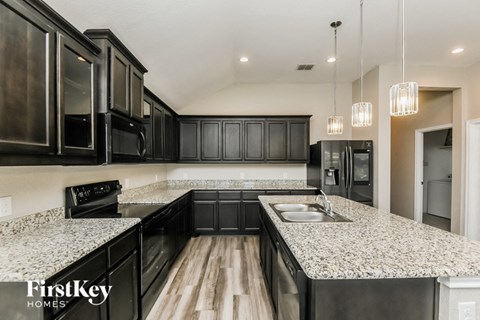A modern kitchen with black cabinets and granite countertops.