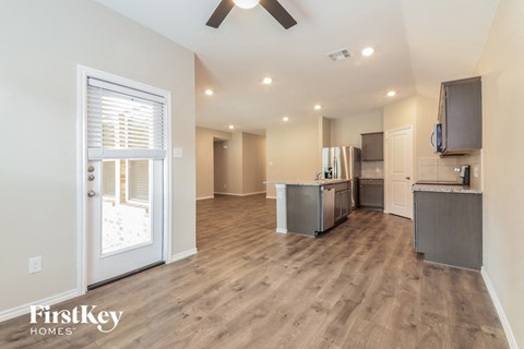 A spacious kitchen with wooden floors and a ceiling fan.