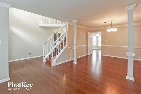 the foyer and living room of an empty house with wood floors and a staircase