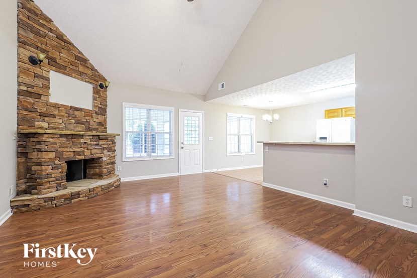 A spacious room with a stone fireplace and wooden floors.
