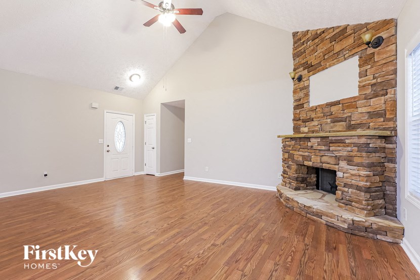 A room with a stone fireplace and wooden floors.
