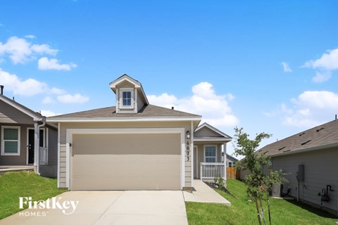 A garage with a brown door is in the middle of a grassy area.