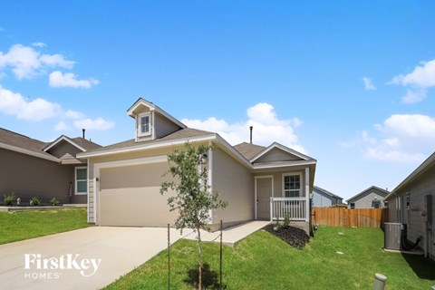 A house with a garage and a tree in front of it.