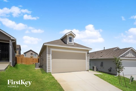 A house with a garage and a tree in front of it.