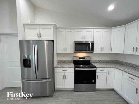A kitchen with a stainless steel refrigerator and a black stove top oven.