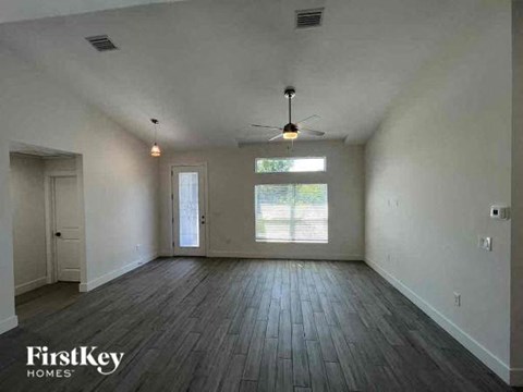 A spacious room with wooden floors and a ceiling fan.