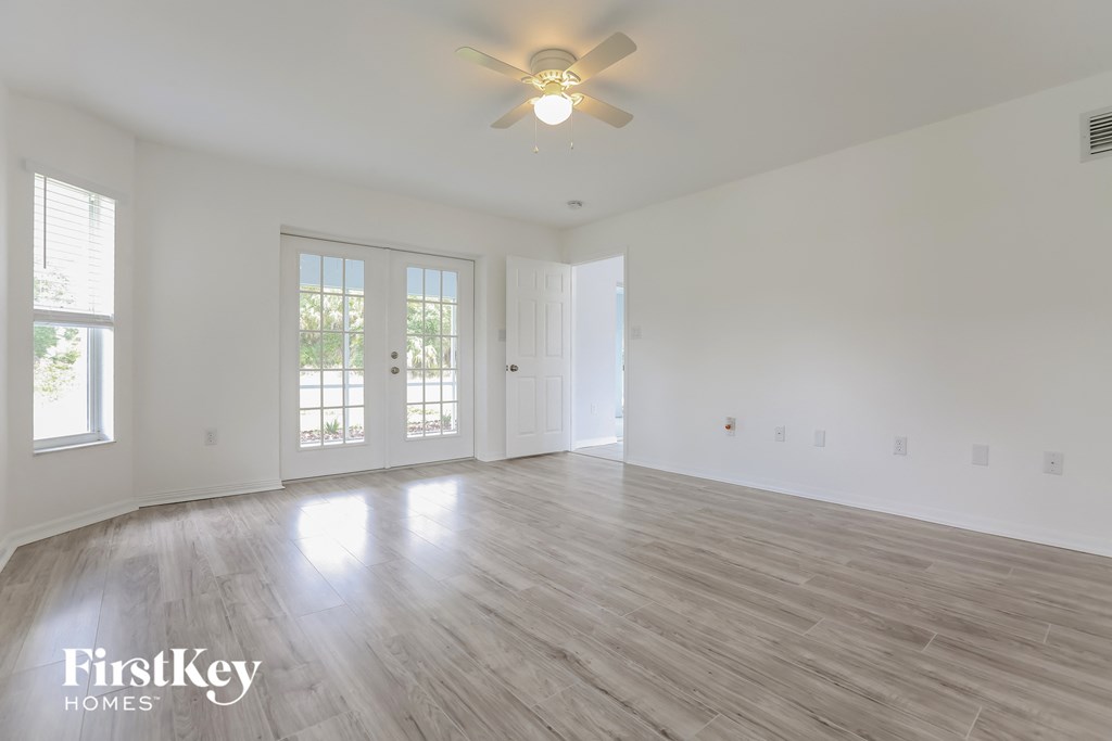 the living room of an empty house with white walls and a ceiling fan