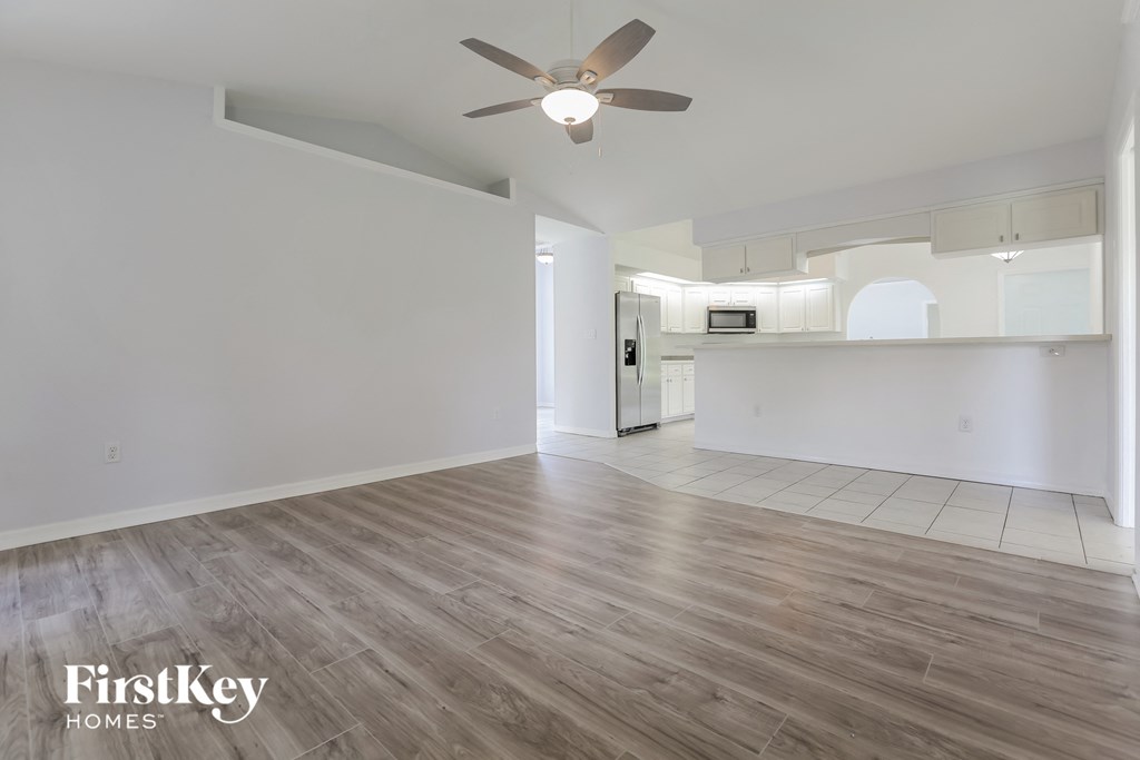 an empty living room with white walls and a ceiling fan