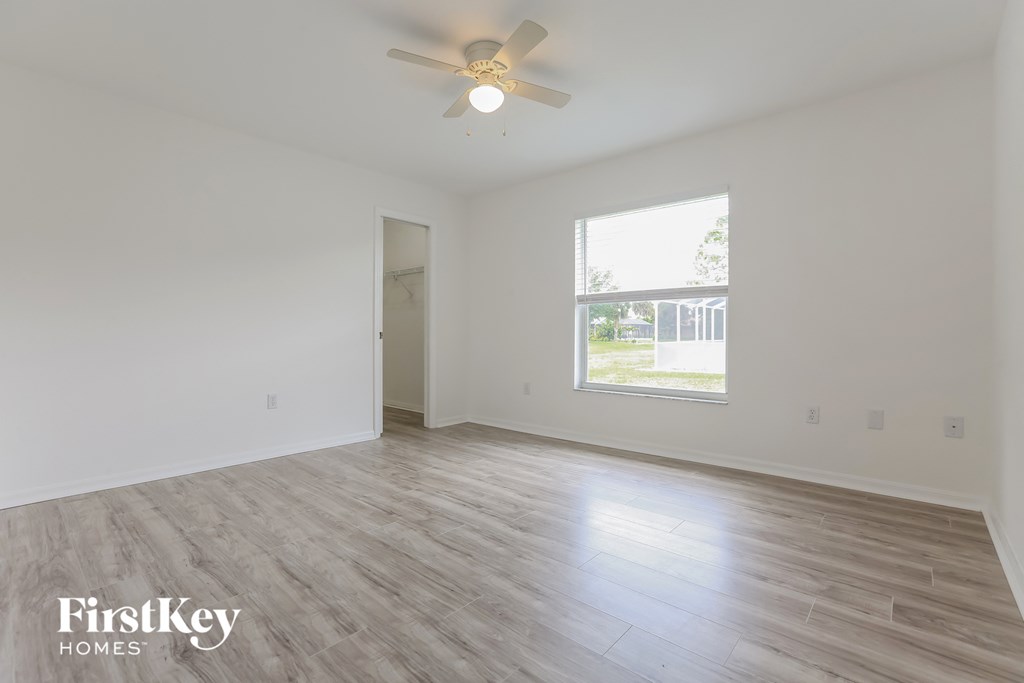 a spacious living room with white walls and a ceiling fan