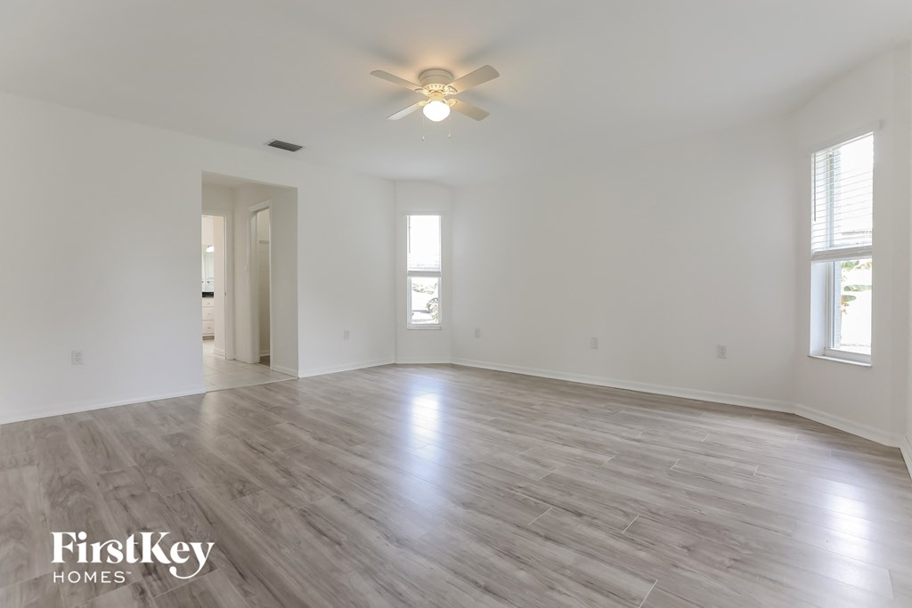 an empty living room with white walls and a ceiling fan