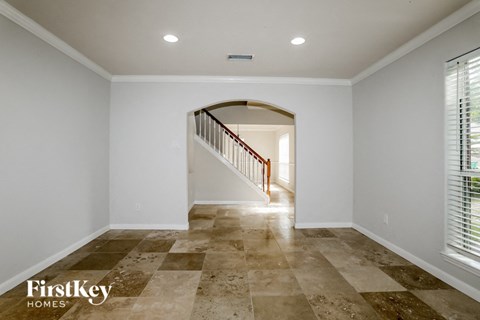 A spacious room with a tiled floor and a staircase leading to another room.