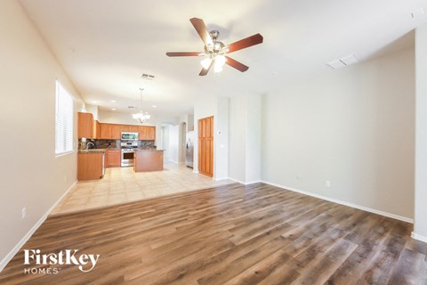 A spacious living room with wooden floors and a ceiling fan.