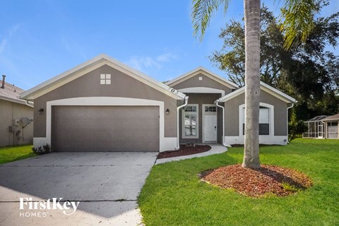 a beige house with a driveway and a palm tree