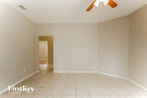 a empty living room with a ceiling fan and tiled floors