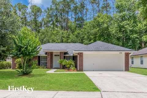 A house with a garage and a driveway in front of it.