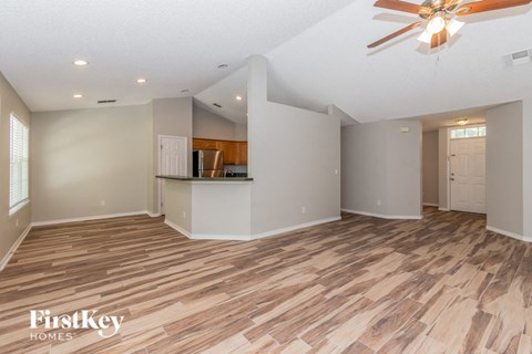 A spacious room with wooden flooring and a ceiling fan.