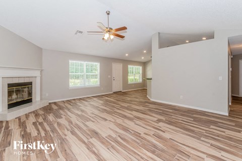 A spacious room with a wood floor and a ceiling fan.