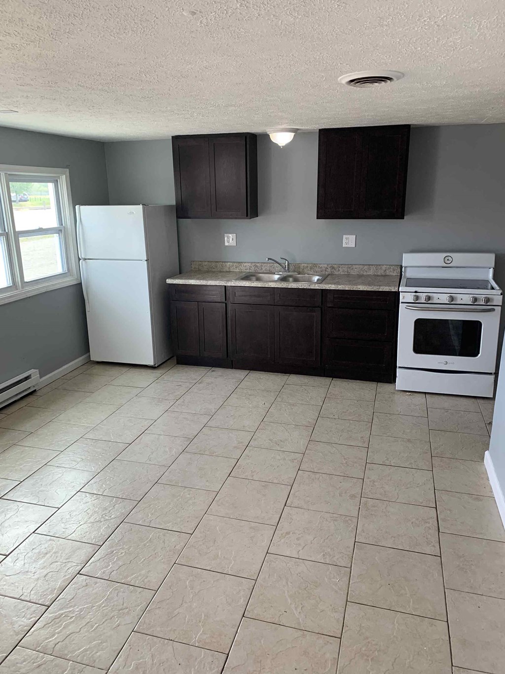 an empty kitchen with a stove refrigerator and a sink