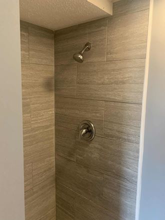 a large shower with brown tile in a bathroom