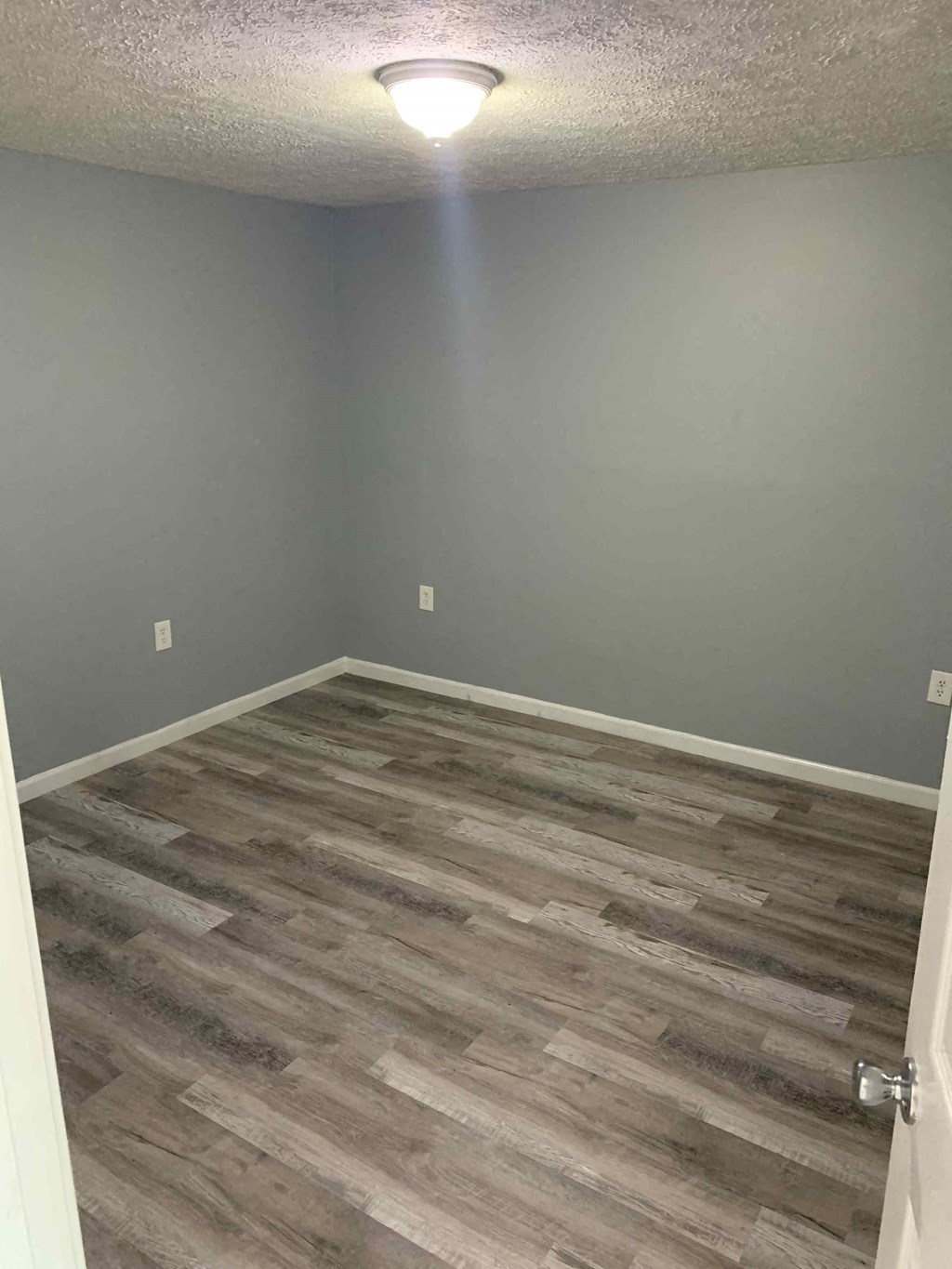 a empty room with wood flooring and a lamp