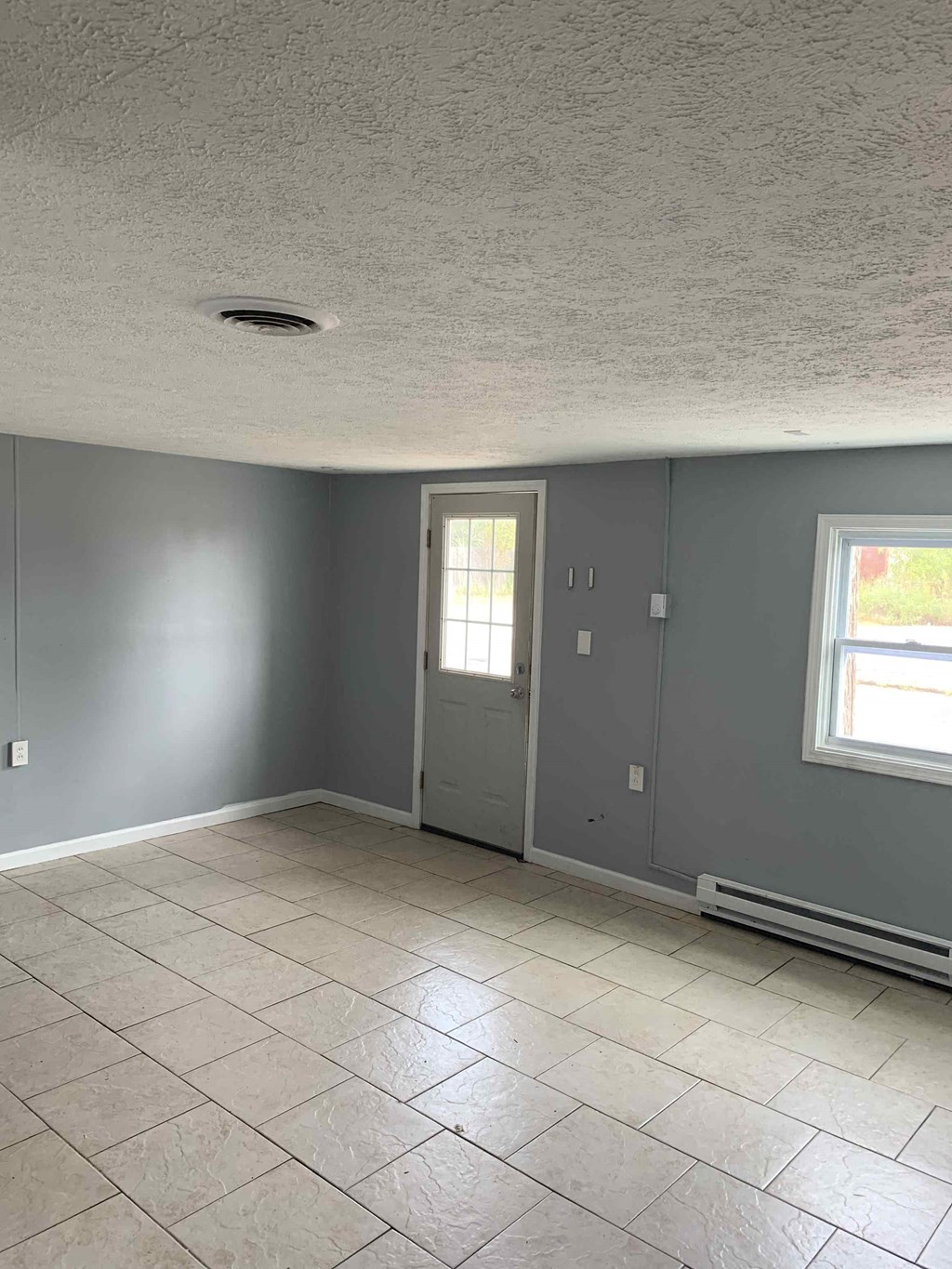 an empty living room with gray walls and a tile floor