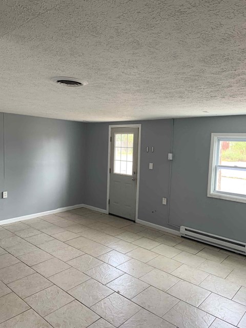 an empty living room with gray walls and a tile floor