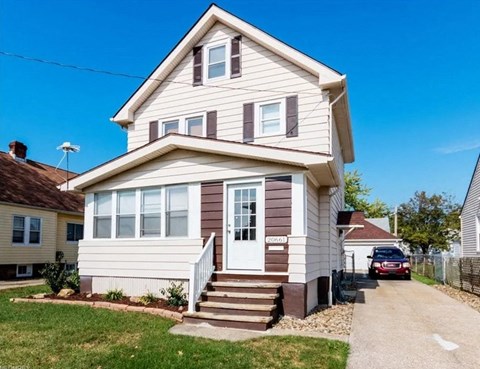 a white house with a red car parked outside of it