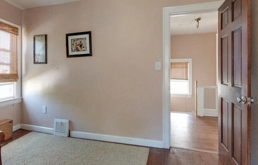 a living room with a door and a hallway to a bedroom
