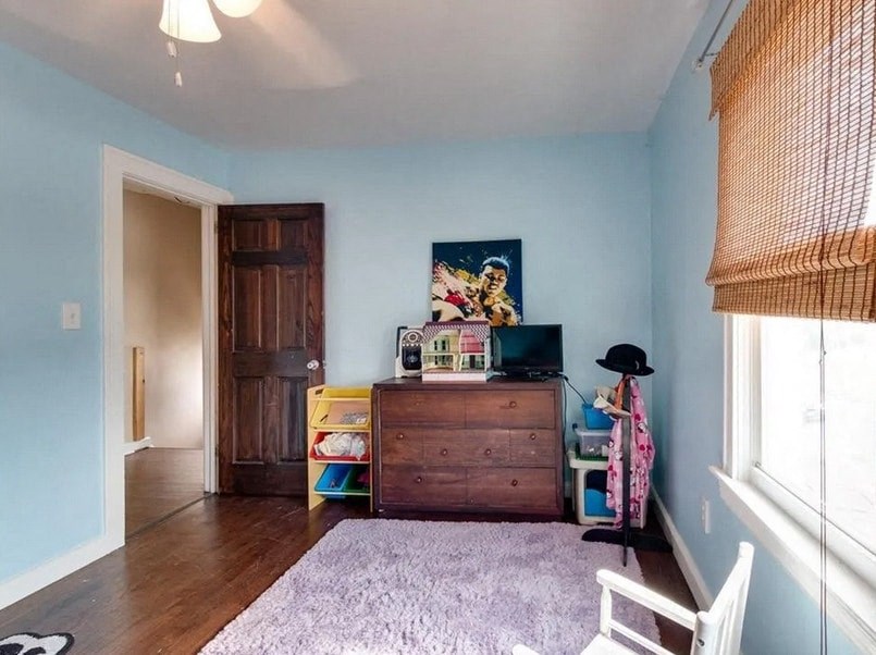 a bedroom with blue walls and a dresser and a rug