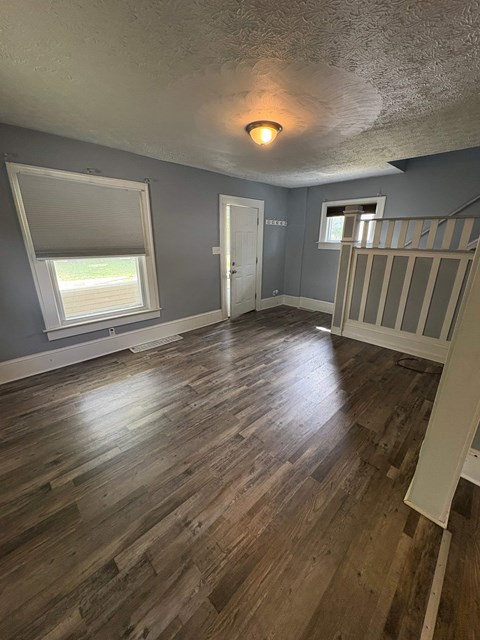 A room with wooden floors and a window with blinds.