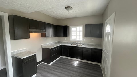 A kitchen with black cabinets and a white door.