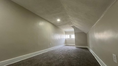 A long, empty hallway with carpeted floors and white walls.
