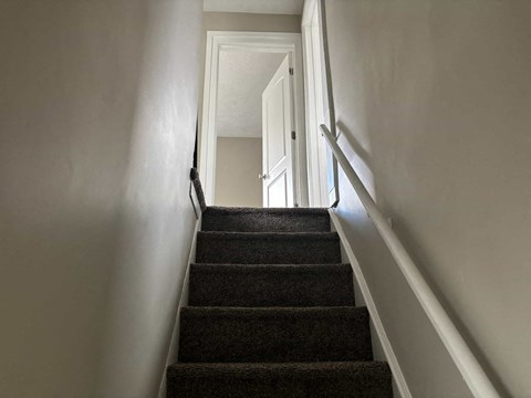 A staircase with a carpeted runner and white walls.