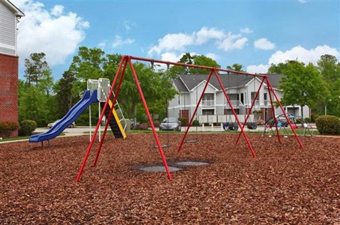 a swing set on a playground in front of a house