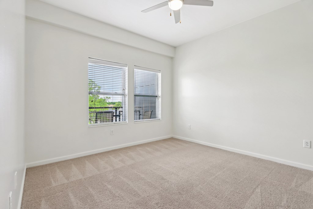 A room with a fan and carpeted floor.