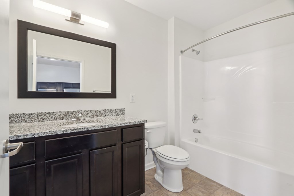 A bathroom with a toilet, sink, and mirror.