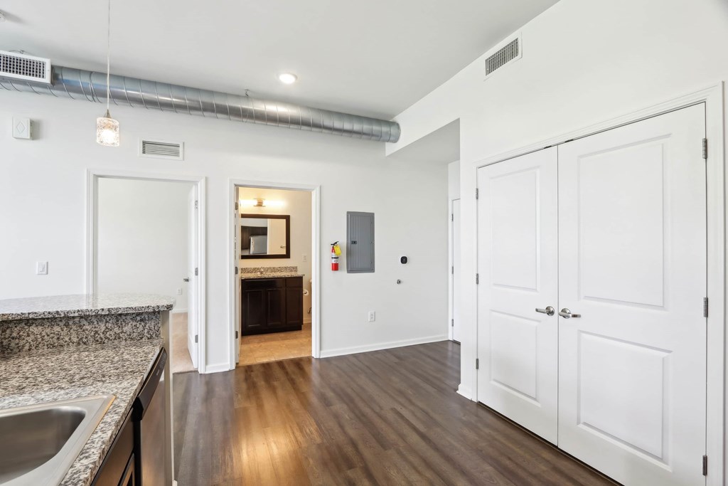 A kitchen with white cabinets and a wooden floor.