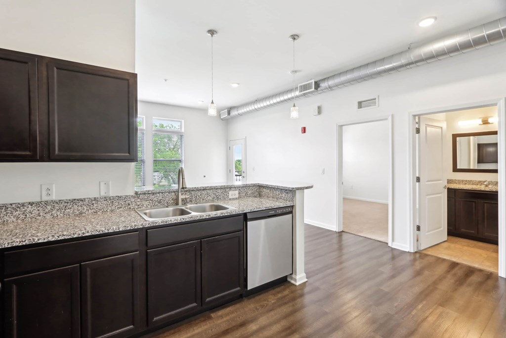 A kitchen with dark brown cabinets and a granite counter top.
