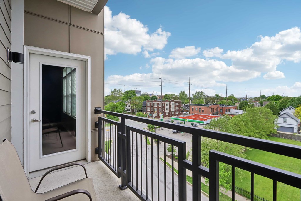 A balcony with a chair and a view of a neighborhood.