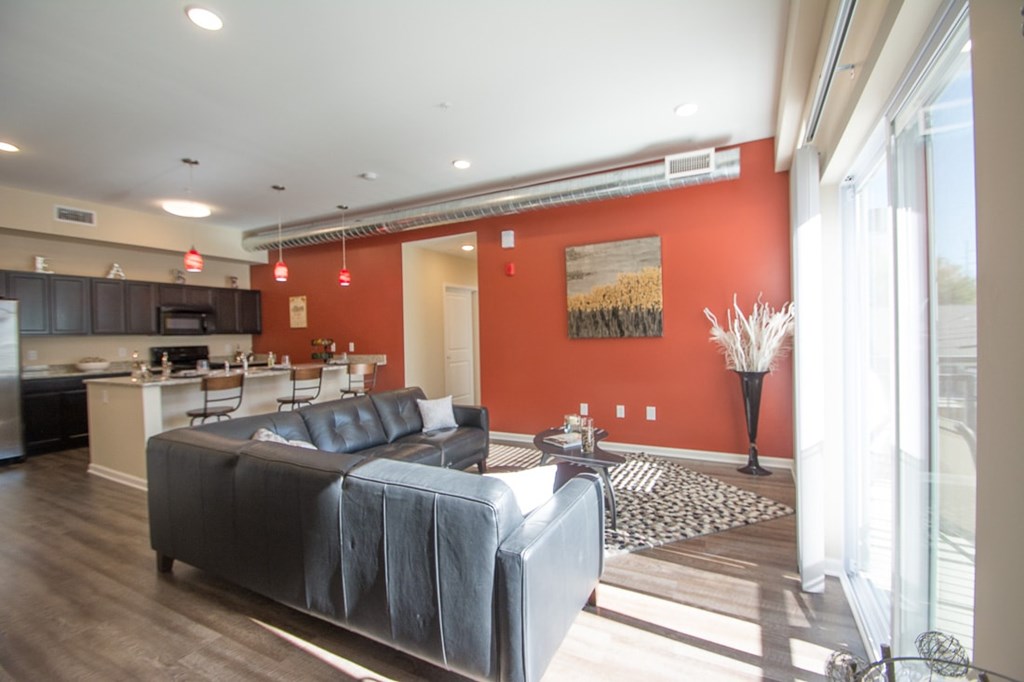 A living room with a grey couch and a red wall.