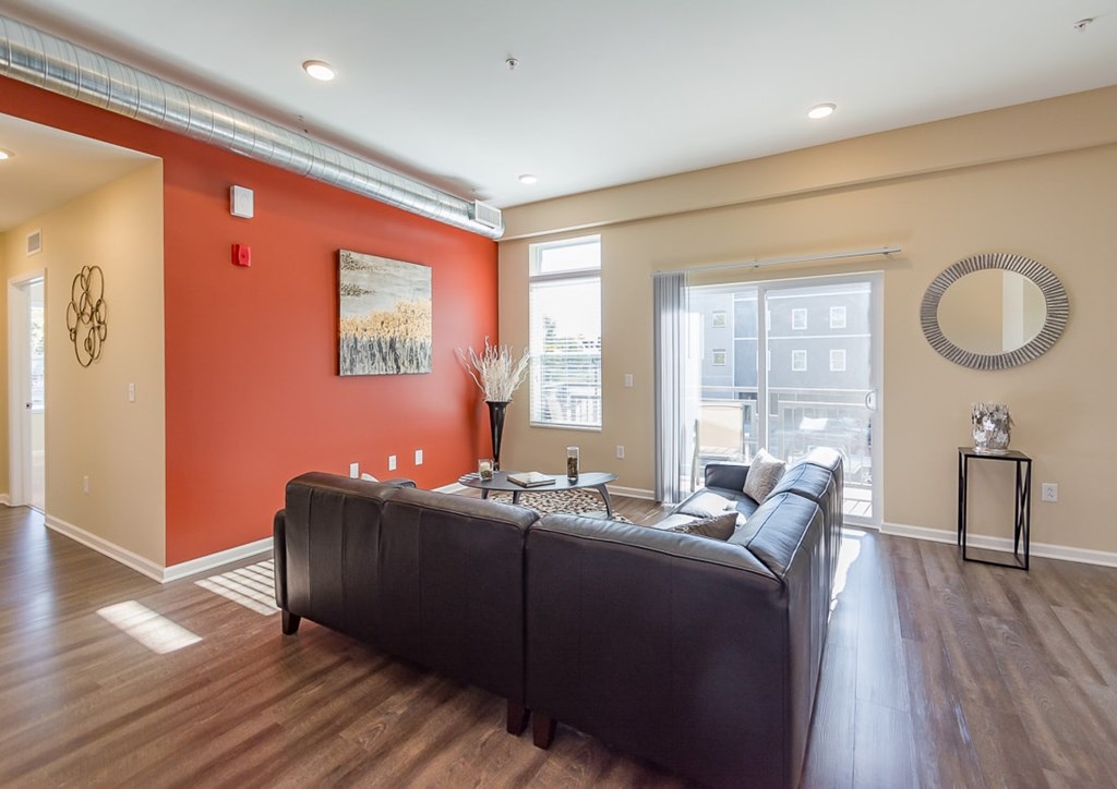 A living room with a black couch and a painting on the wall.
